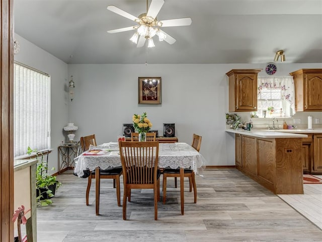 dining space with light wood finished floors, ceiling fan, baseboards, and vaulted ceiling