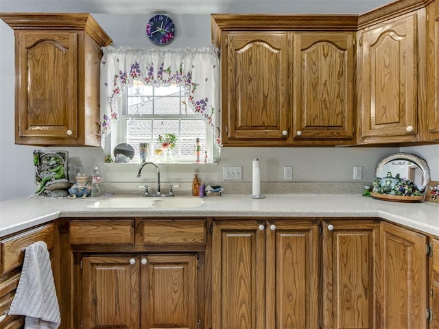 kitchen featuring brown cabinetry, light countertops, and a sink