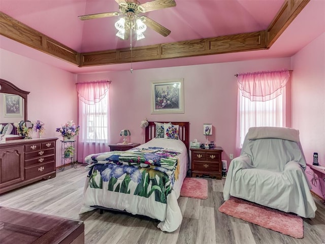 bedroom featuring a ceiling fan, a tray ceiling, and wood finished floors