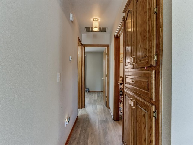 hall featuring light wood-style flooring and visible vents