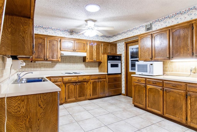 kitchen featuring sink, decorative backsplash, white appliances, ceiling fan, and a textured ceiling