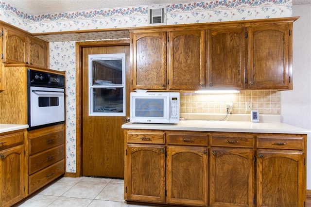 kitchen with tasteful backsplash, white appliances, and light tile patterned flooring