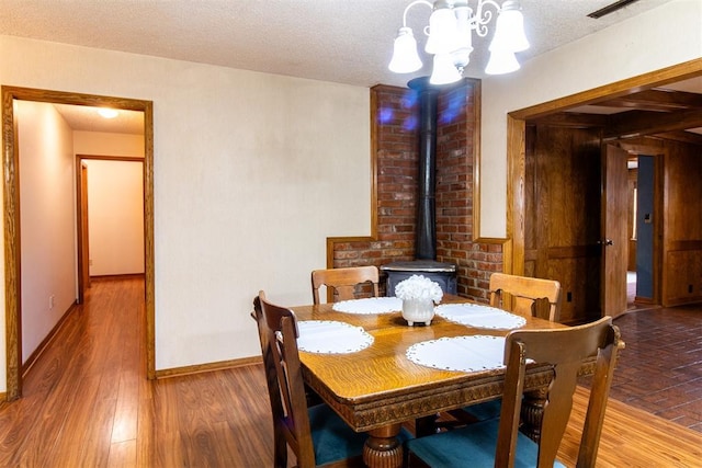 dining area with wood-type flooring, a chandelier, and a textured ceiling