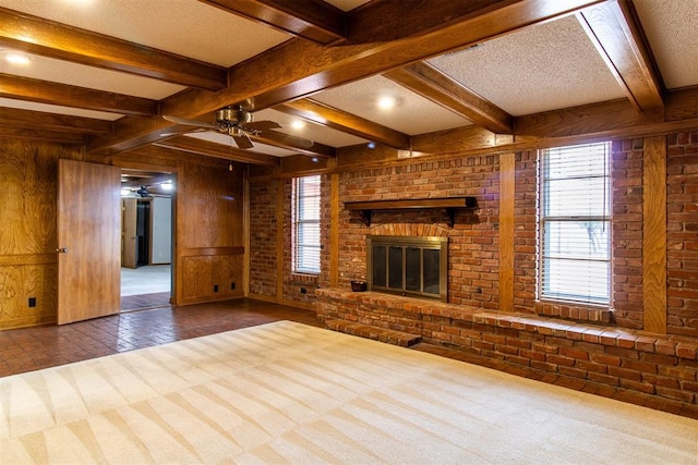 unfurnished living room with a fireplace, a wealth of natural light, wooden walls, and brick wall