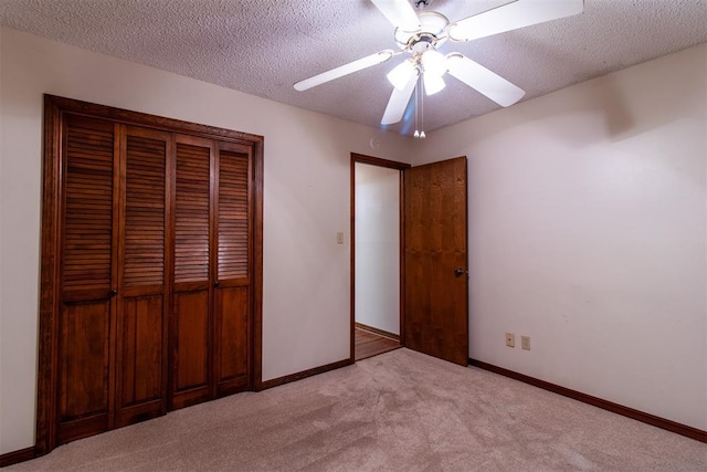 unfurnished bedroom with ceiling fan, light colored carpet, a closet, and a textured ceiling