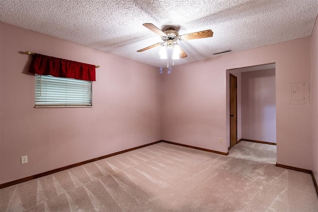 empty room with ceiling fan, light colored carpet, and a textured ceiling