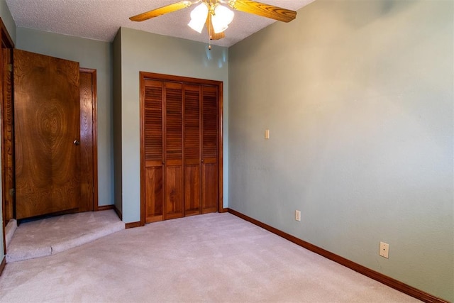 unfurnished bedroom with ceiling fan, light carpet, a closet, and a textured ceiling