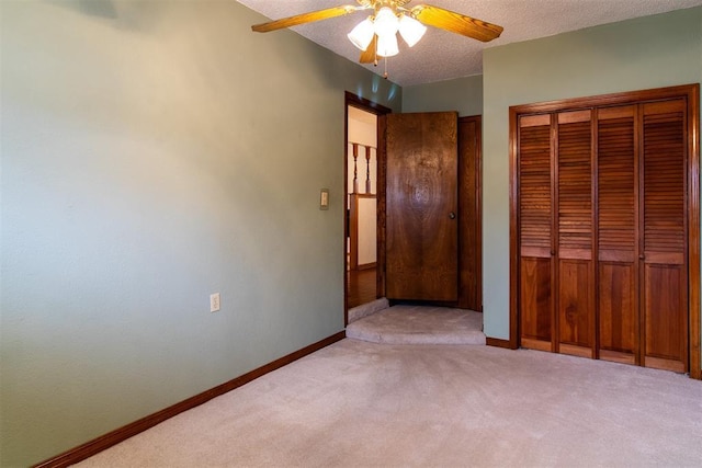 unfurnished bedroom with light carpet, ceiling fan, a closet, and a textured ceiling