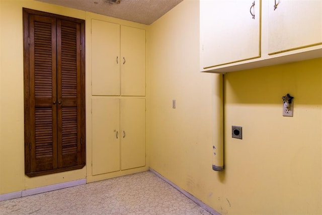 laundry area featuring cabinets, hookup for an electric dryer, and a textured ceiling