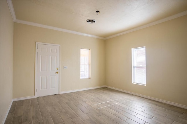 spare room with ornamental molding, a wealth of natural light, and light hardwood / wood-style floors