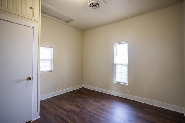 empty room with a healthy amount of sunlight and dark wood-type flooring