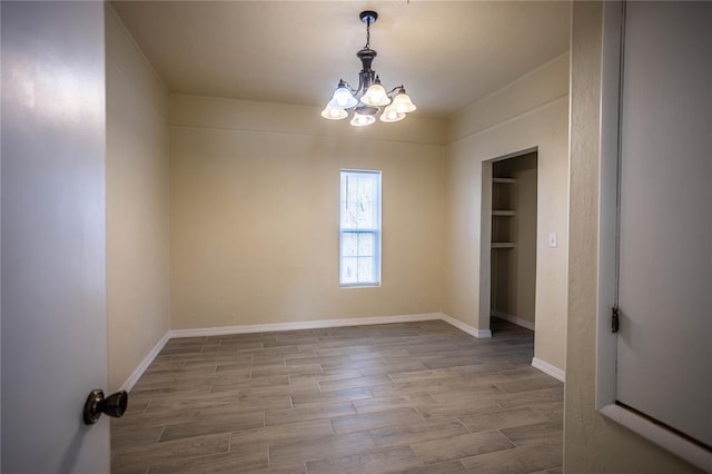 unfurnished room featuring an inviting chandelier, built in shelves, and light hardwood / wood-style floors