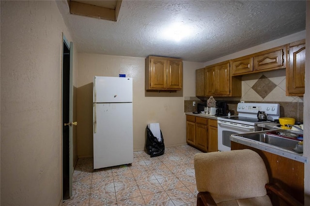 kitchen with sink, backsplash, white appliances, light tile patterned floors, and a textured ceiling