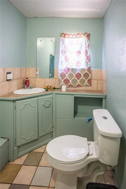 bathroom with tile patterned floors, toilet, a textured ceiling, vanity, and backsplash