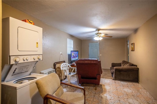 interior space with ceiling fan, a textured ceiling, and stacked washer / dryer