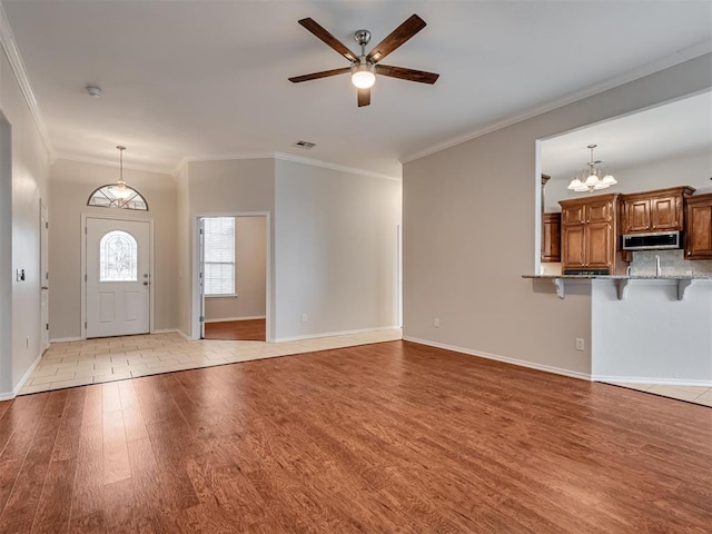 entryway featuring ceiling fan with notable chandelier, light hardwood / wood-style flooring, and ornamental molding