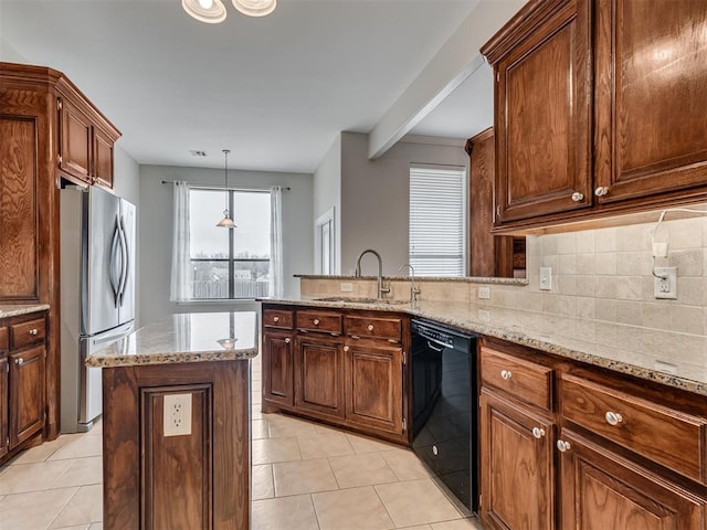 kitchen featuring sink, light stone counters, stainless steel fridge, black dishwasher, and a kitchen island