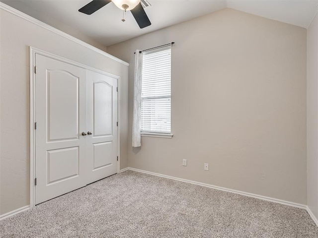 unfurnished bedroom with vaulted ceiling, a closet, ceiling fan, and carpet flooring