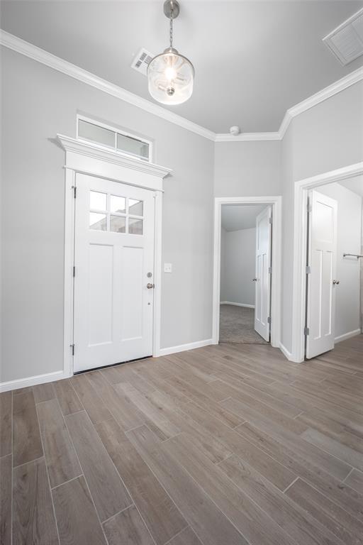 entryway with wood-type flooring and ornamental molding