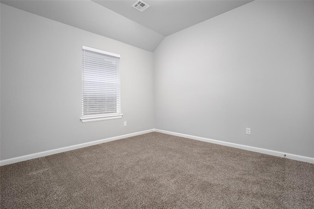 carpeted spare room featuring vaulted ceiling