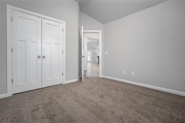 unfurnished bedroom with vaulted ceiling, carpet floors, and a closet