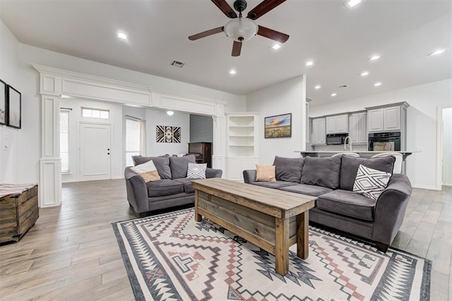 living room featuring sink, light hardwood / wood-style floors, and ceiling fan