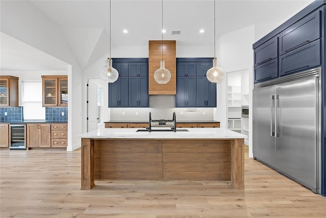 kitchen with pendant lighting, sink, beverage cooler, stainless steel built in fridge, and light wood-type flooring