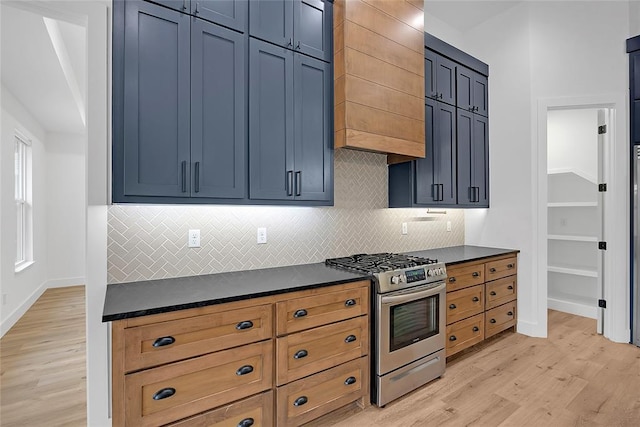 kitchen featuring custom exhaust hood, gas range, light hardwood / wood-style floors, and decorative backsplash