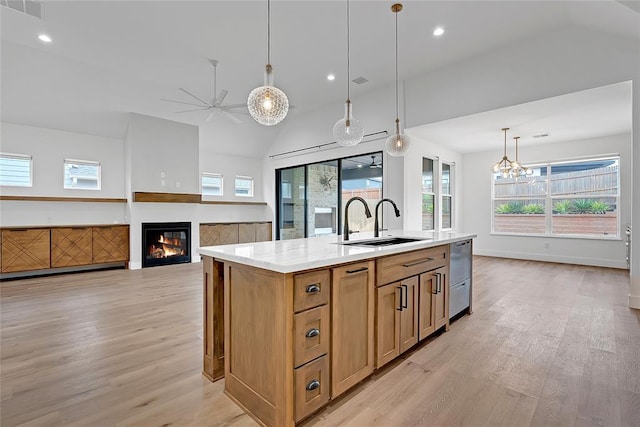 kitchen featuring lofted ceiling, sink, light hardwood / wood-style flooring, a center island with sink, and decorative light fixtures