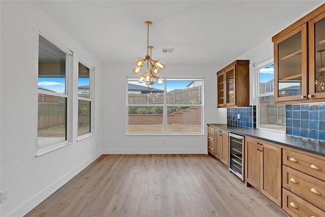 kitchen with light hardwood / wood-style flooring, an inviting chandelier, wine cooler, tasteful backsplash, and decorative light fixtures