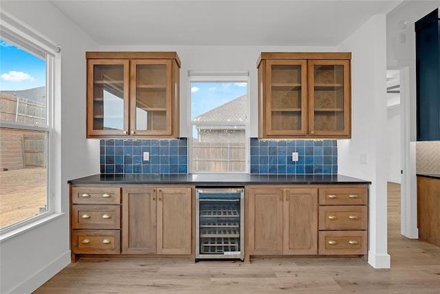 bar featuring wine cooler, light hardwood / wood-style flooring, and tasteful backsplash