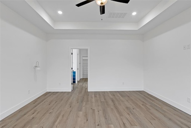 spare room with ceiling fan, a tray ceiling, and light hardwood / wood-style floors