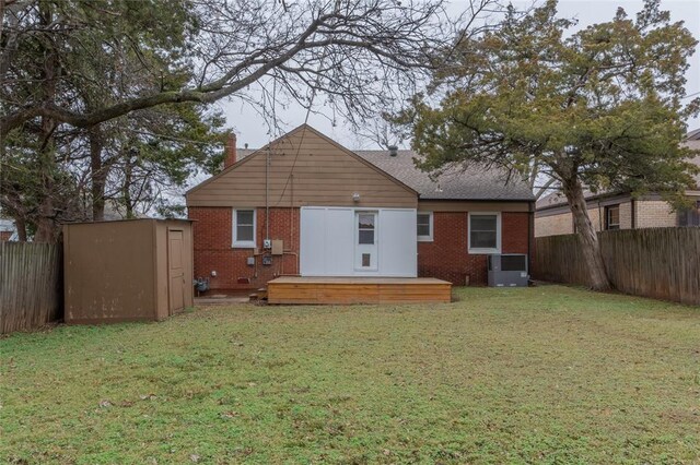 rear view of house with a wooden deck, a yard, and a storage shed