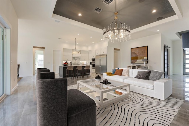 living room with light wood-style flooring, a tray ceiling, a chandelier, and a healthy amount of sunlight