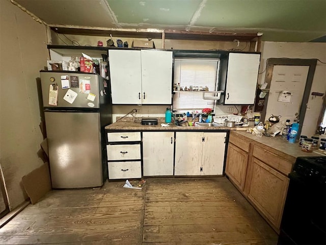 kitchen with white cabinetry, sink, stainless steel refrigerator, and black gas range