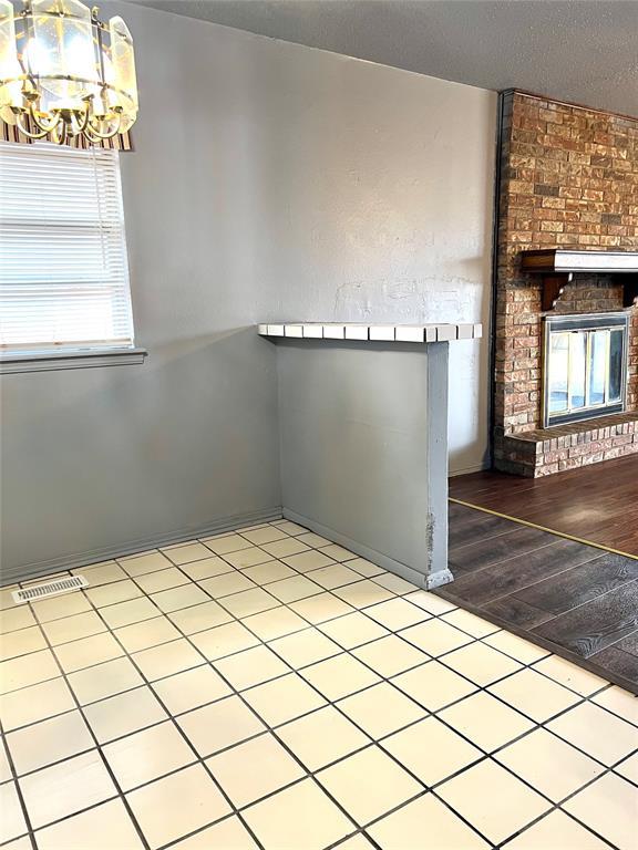 spare room with light hardwood / wood-style flooring, a fireplace, a chandelier, and a textured ceiling