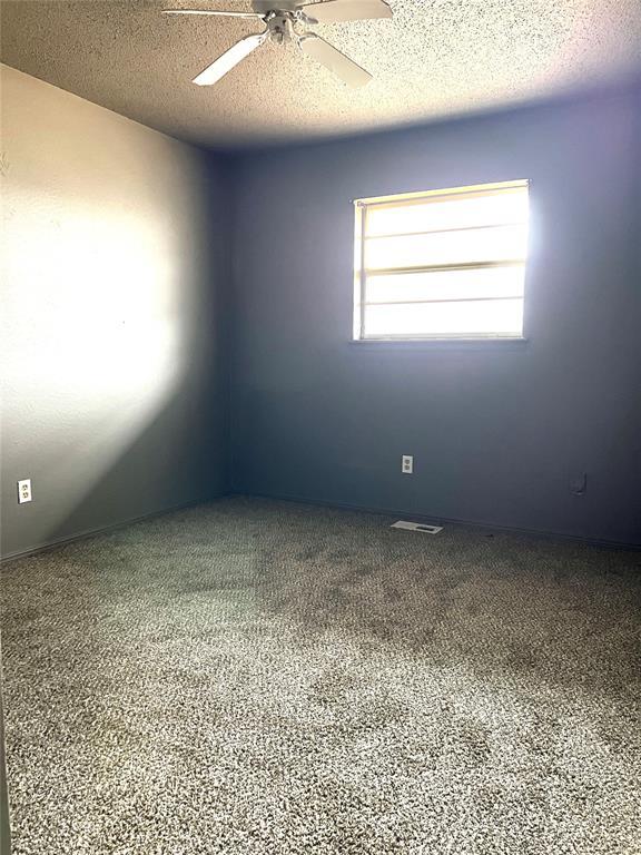 empty room with carpet floors, a textured ceiling, and ceiling fan