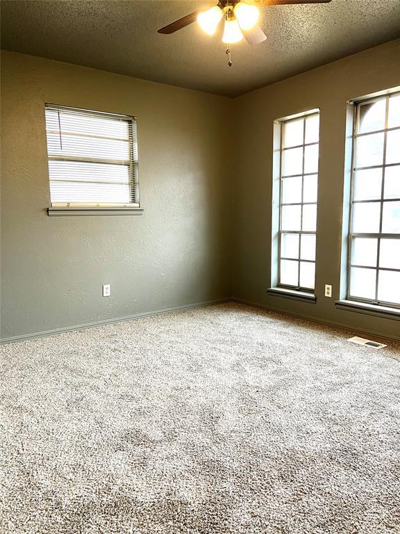 carpeted empty room featuring ceiling fan and a textured ceiling