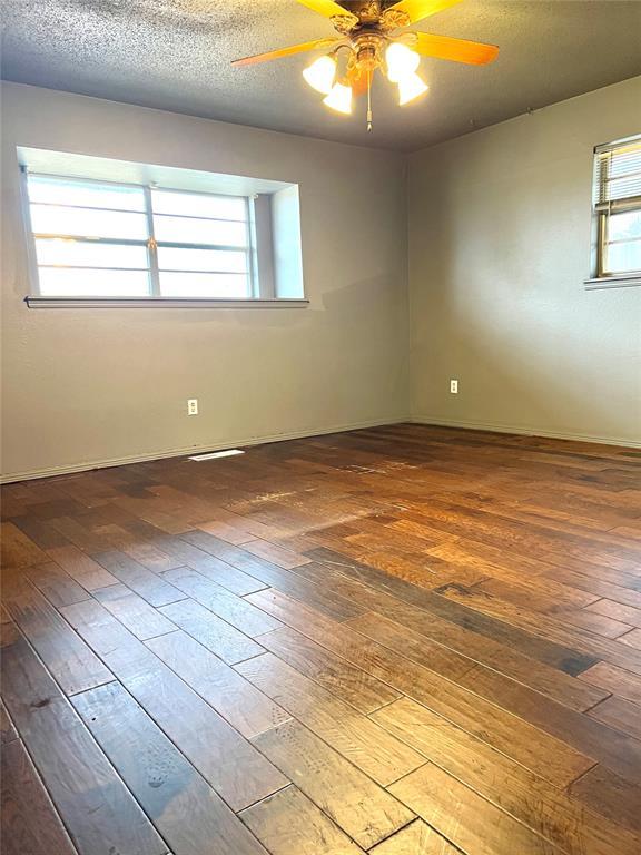 empty room with ceiling fan, dark hardwood / wood-style floors, and a textured ceiling