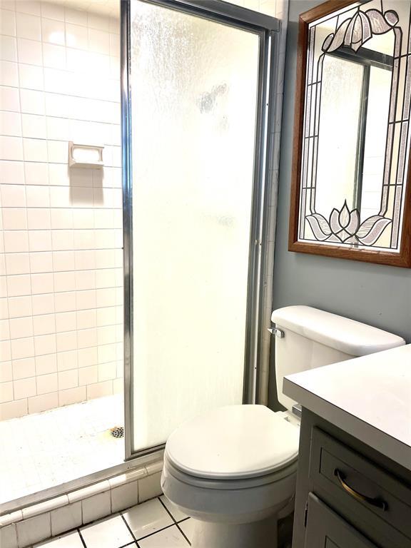 bathroom featuring vanity, an enclosed shower, tile patterned floors, and toilet