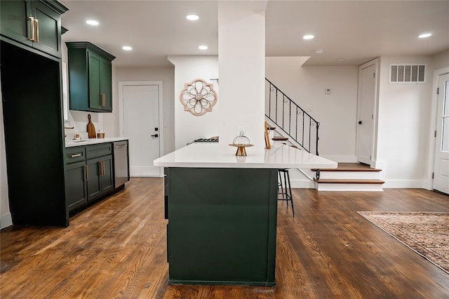 kitchen featuring a breakfast bar area, stainless steel dishwasher, dark hardwood / wood-style flooring, and green cabinetry