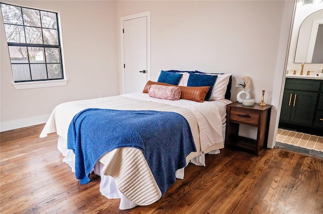 bedroom with ensuite bath and dark hardwood / wood-style flooring