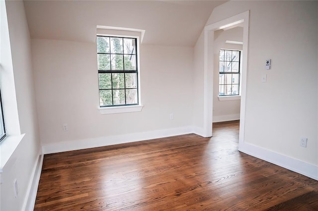 unfurnished room with a wealth of natural light, dark hardwood / wood-style floors, and vaulted ceiling