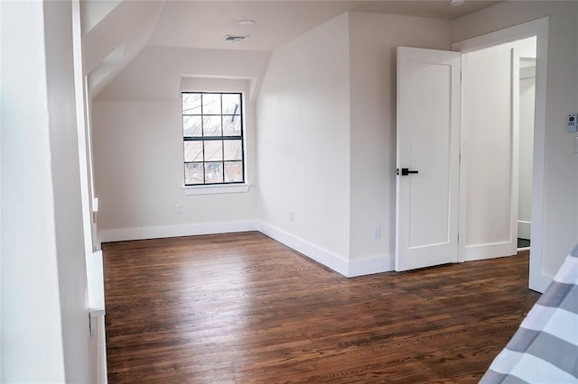 additional living space featuring dark wood-type flooring and lofted ceiling