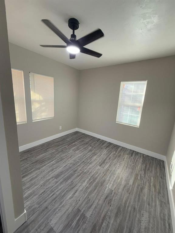 unfurnished room with dark wood-type flooring and ceiling fan