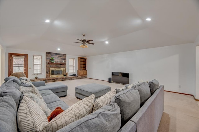 carpeted living room featuring a brick fireplace, lofted ceiling, ceiling fan, and built in shelves