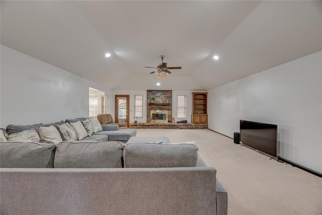 carpeted living room with ceiling fan, lofted ceiling, a fireplace, and built in shelves