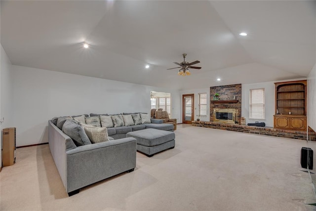 living room with ceiling fan, lofted ceiling, light carpet, and a fireplace