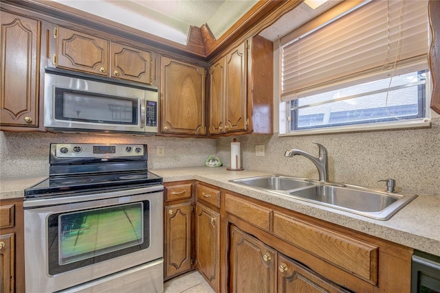 kitchen featuring sink, decorative backsplash, light tile patterned floors, and appliances with stainless steel finishes