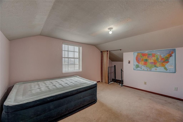 carpeted bedroom featuring vaulted ceiling and a textured ceiling